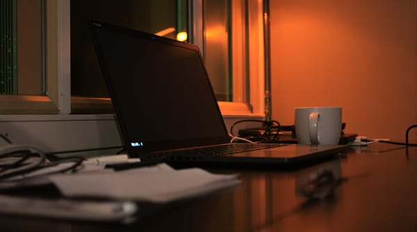 A laptop with a terminal open on a desk late at night, lit by a street lamp outside